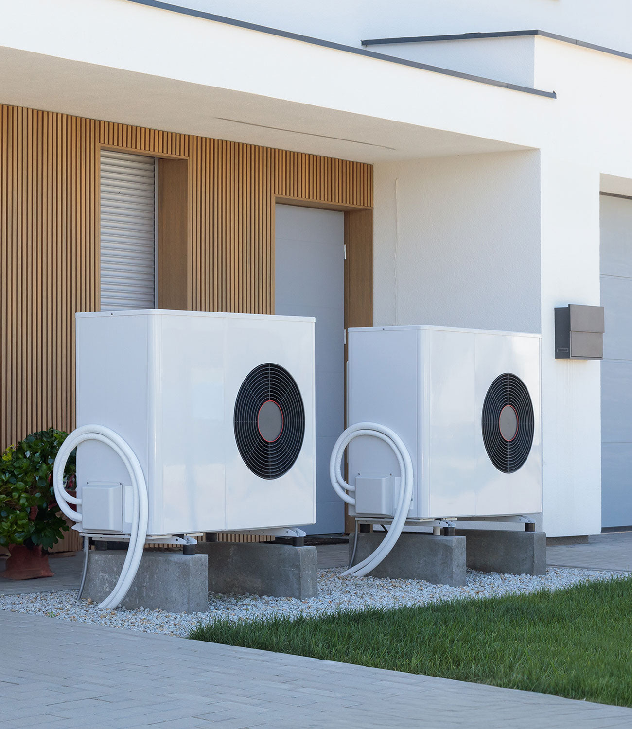 Weisse Luftwärmepumpe vor einem neu gebauten Haus