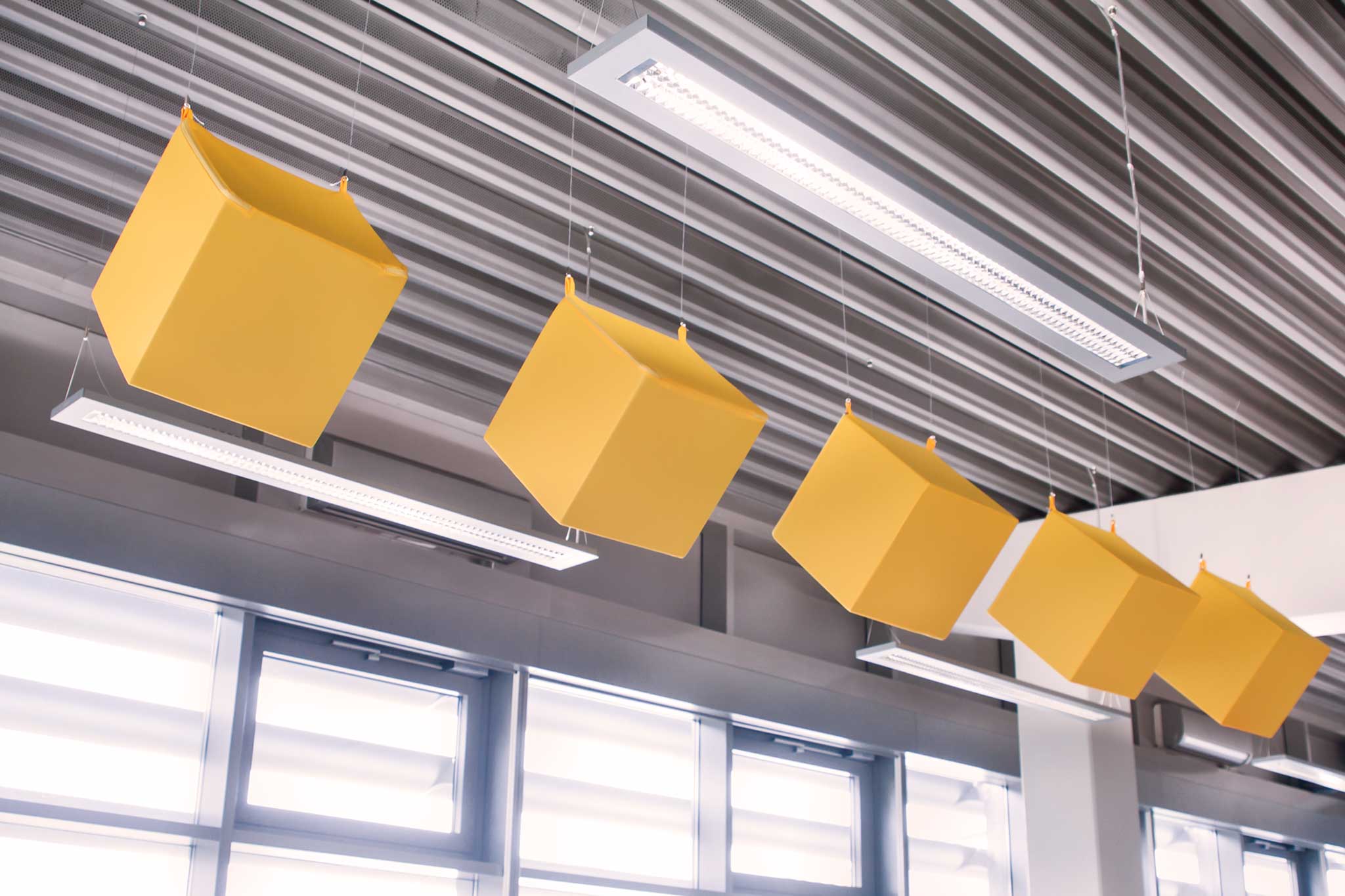 Mehrere Akustikwürfel hängend an einer Industriehallendecke