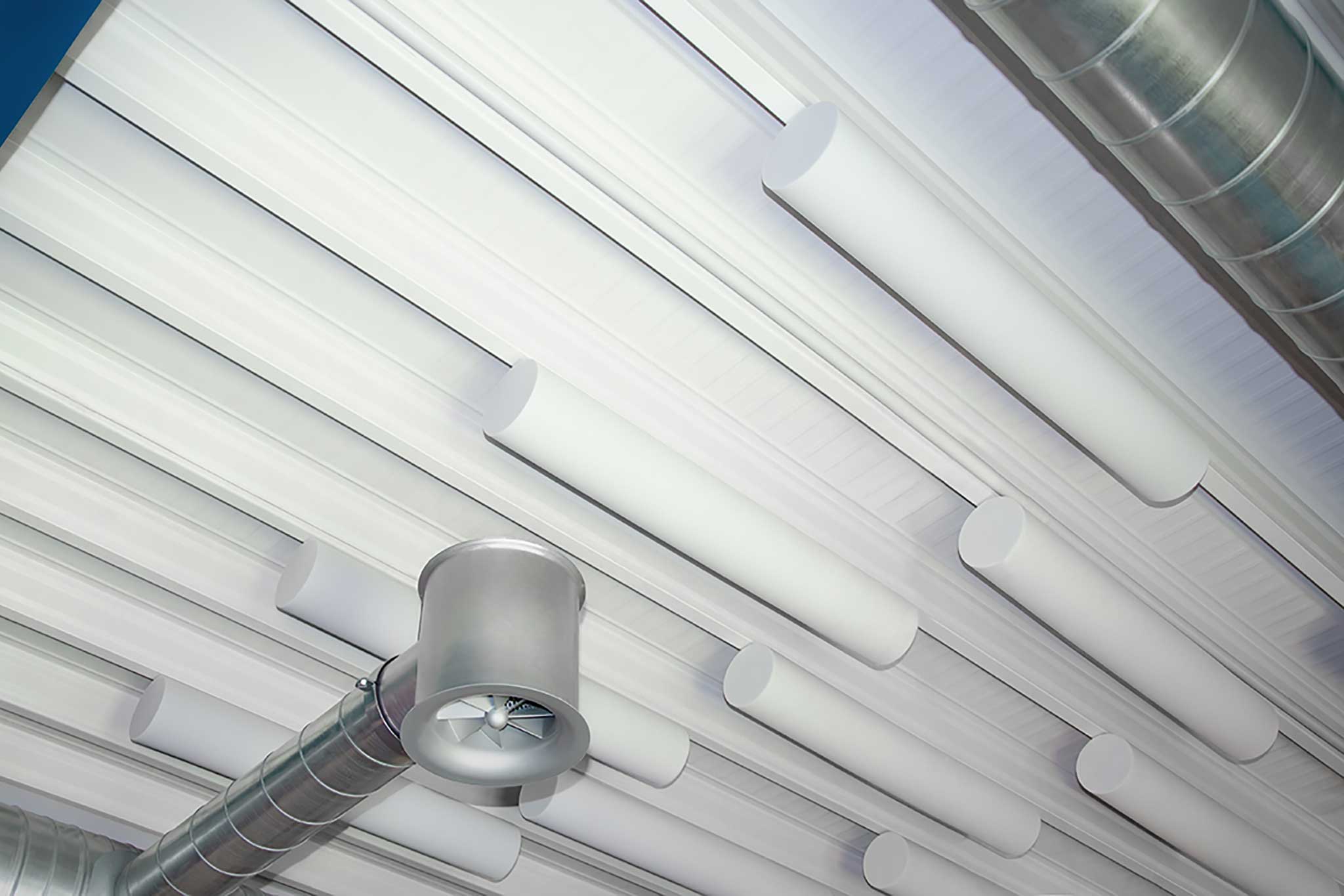 Weisse Akustikzylinder aus Basotect an Decke einer Industriehalle