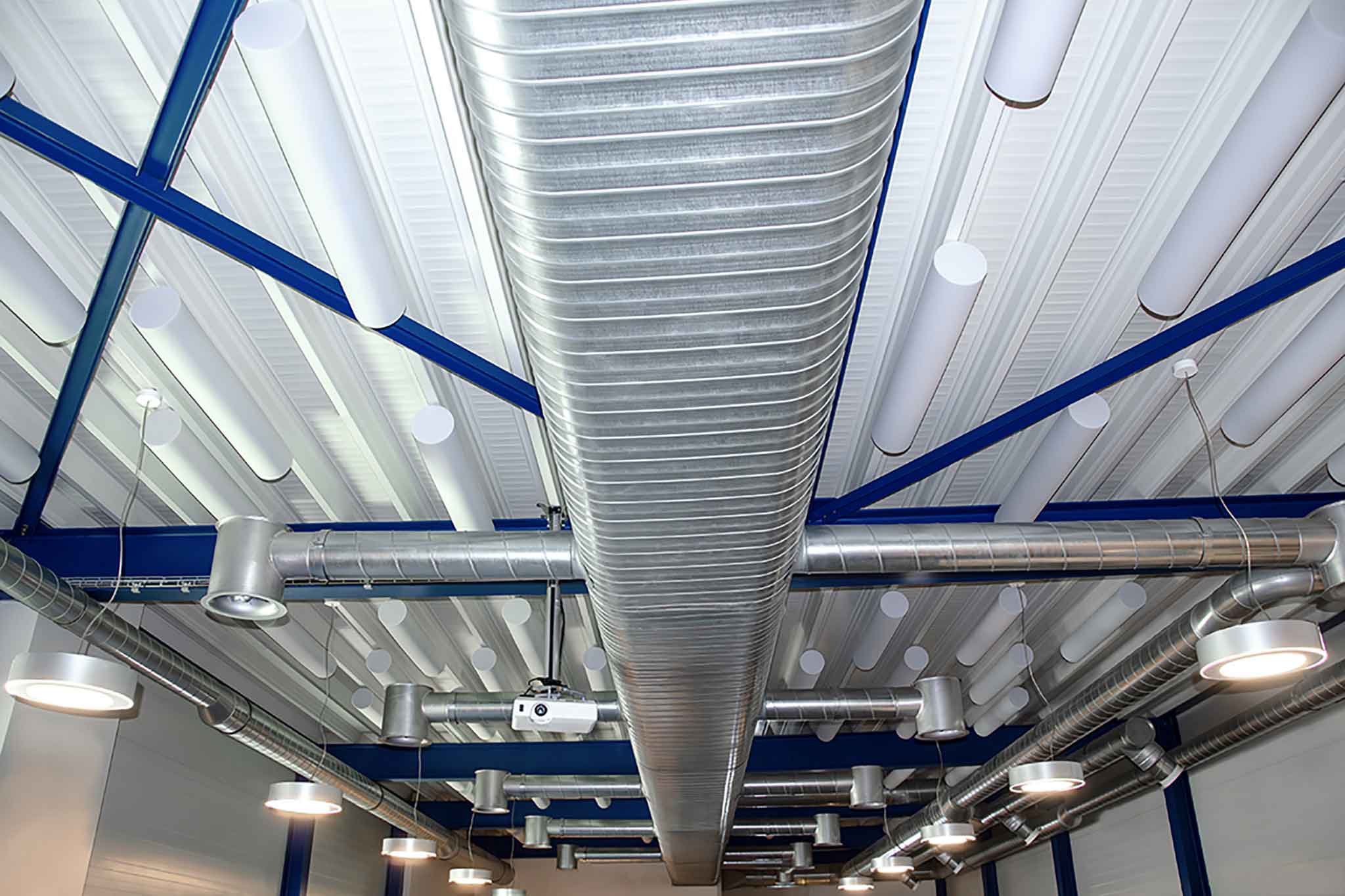 Weisse Akustikzylinder aus Basotect an Decke einer Industriehalle