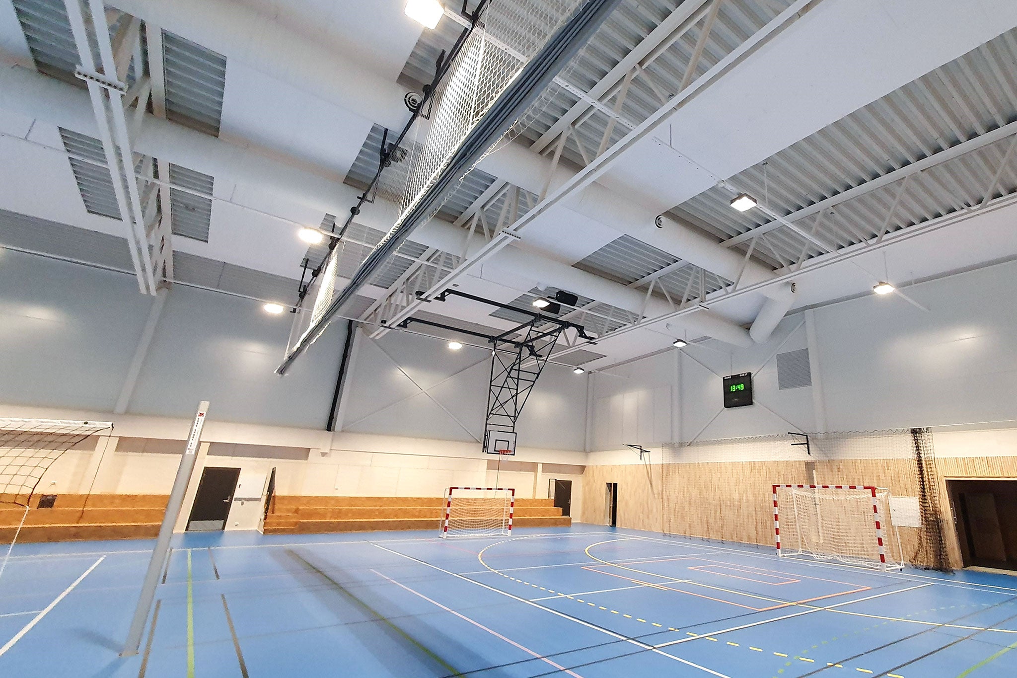 Sporthalle mit blauem Boden, Fussballtor, Basketballkorb und Schallabsorbern an der Decke.